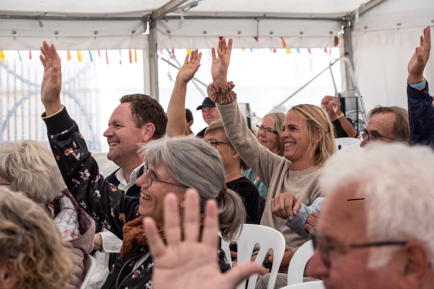 Publikum i et telt rækker hænderne op